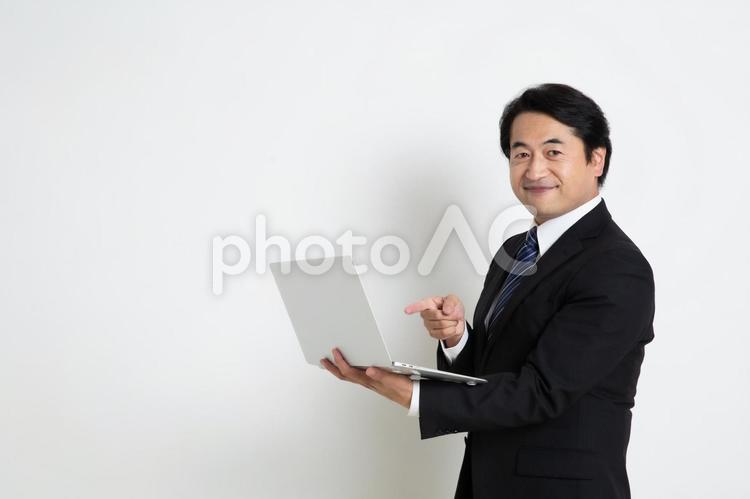 笑顔でパソコンを指差している中年のサラリーマン男性（コピースペース） 中年,上司,会社員の写真素材