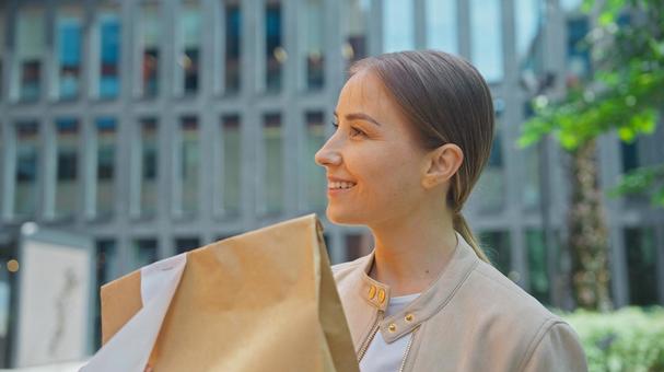 ビルの前でフードデリバリーを受け取っている笑顔の女性 配達,フードデリバリー,デリバリーの写真素材