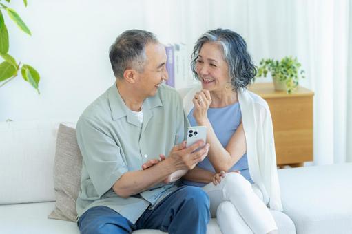 リビングでスマホを見るシニア夫婦 スマホ,シニア,笑顔の写真素材