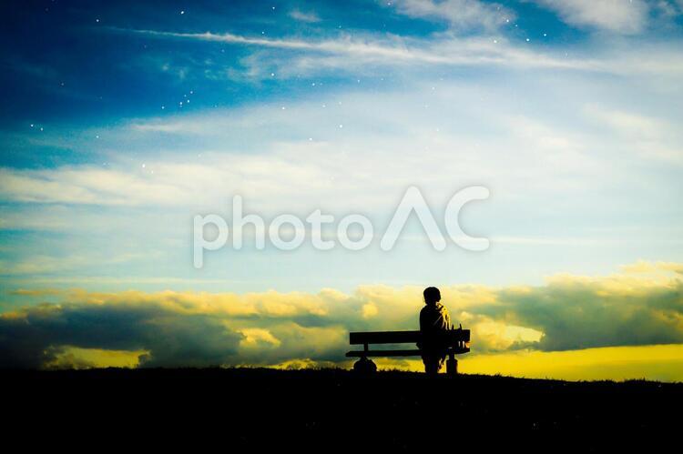 夕焼けの丘に座る女性のシルエットと星空 夕焼け,丘,シルエットの写真素材