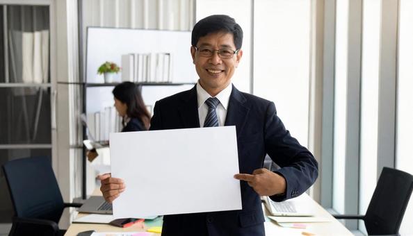 ホワイトトボードを掲げるサラリーマンの写真