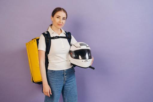 ヘルメットを抱えるフードデリバリーの女性 配達,フードデリバリー,デリバリーの写真素材