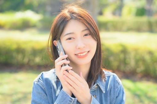 公園で電話をする女性 公園で電話をする女性の写真