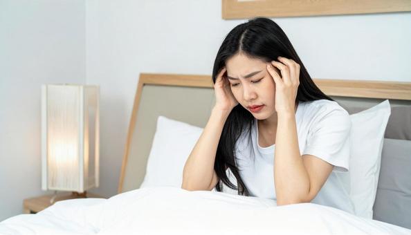 起床時に寝不足と疲労と体調不良の女性 起床時に寝不足と疲労と体調不良の女性の写真