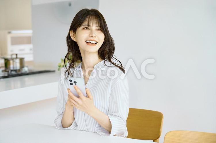 スマホを持つ主婦　女性　リビング　 スマホ,女性,主婦の写真素材