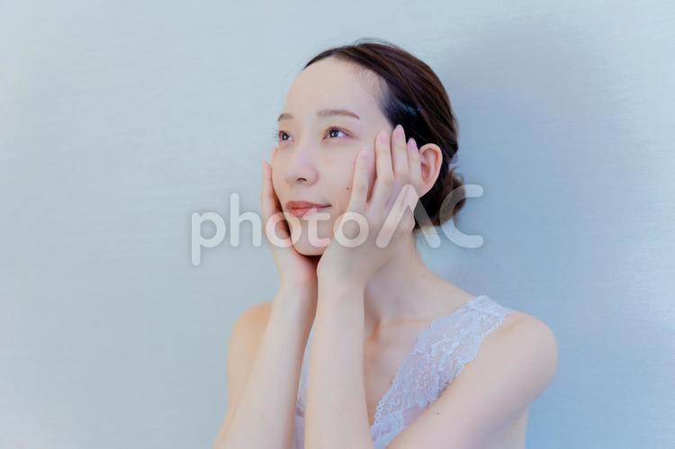 頬に手を当て微笑む女性 女性,美容,顔の写真素材