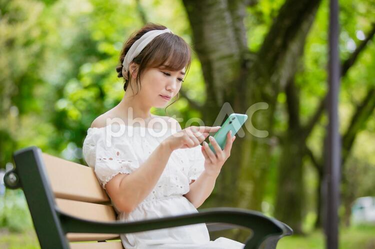 公園のベンチでスマホを使う女性 スマホ,女性,困るの写真素材