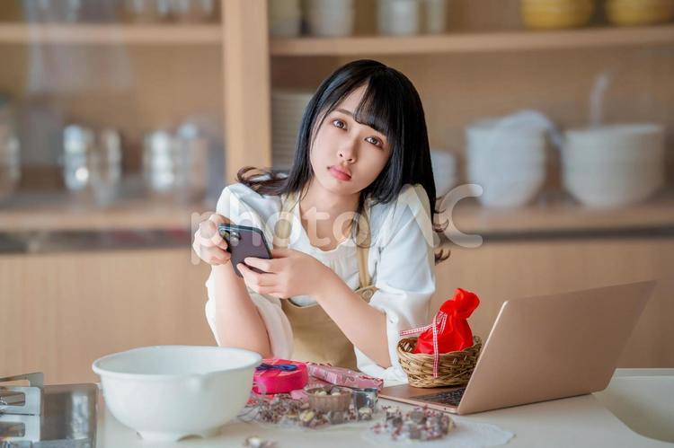 携帯電話とパソコンをいじる女性パティシエ バレンタイン,チョコ,手作りチョコの写真素材