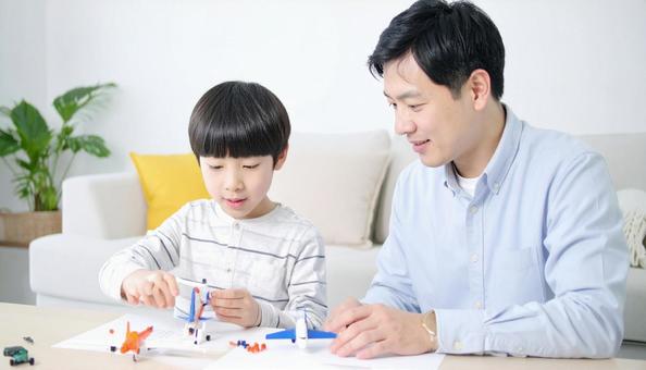 父親と一緒にプラモデルを作る男の子 父親と一緒にプラモデルを作る男の子の写真
