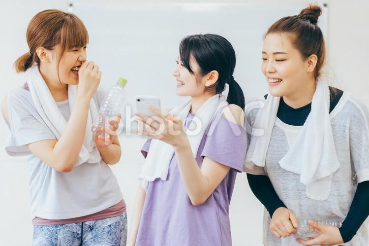 スポーツジムでスマホを見て談笑する女性たち スポーツジム,スマホ,体験レッスンの写真素材