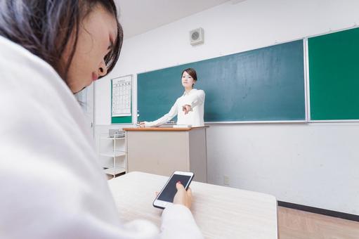 授業中にスマホを使う学生と注意する教師 授業中にスマホを使う学生と注意する教師の写真