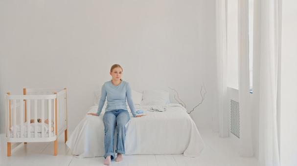 ベッドに座り休憩する女性 ベッドに座り休憩する女性 女性,育児疲れ,疲れたの写真素材