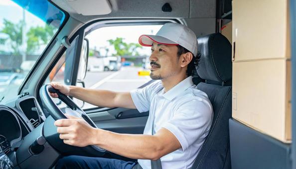 トラックを運転する男性ドライバーの横顔 トラックを運転する男性ドライバーの横顔の写真