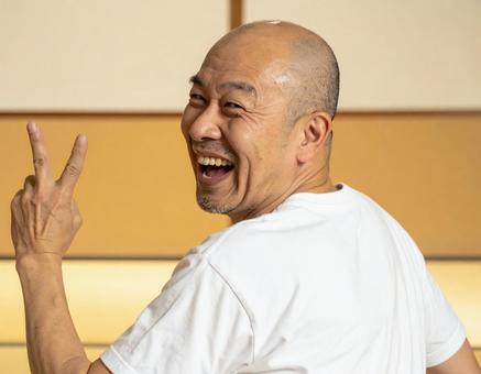 ピースをしながら振り向く男性 ピースをしながら振り向く男性の写真