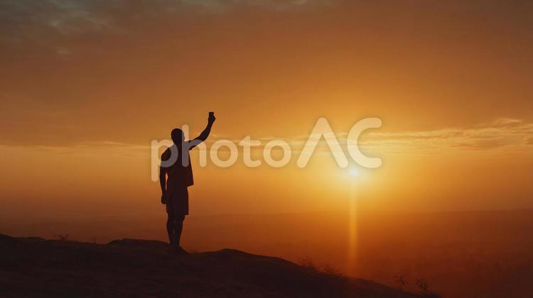 絶景を撮影する男性 男性,シルエット,夕焼けの写真素材