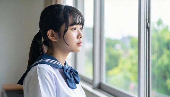 学校の教室で窓の外を眺める女子高校生横顔 学校の教室で窓の外を眺める女子高校生横顔の写真