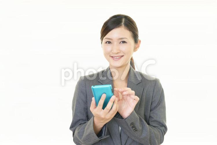 スマートフォンを持つ笑顔の女性 女性,ビジネスウーマン,女の写真素材