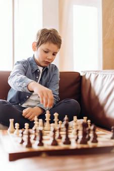 ソファで一人でチェスをしている男の子 ソファで一人でチェスをしている男の子の写真