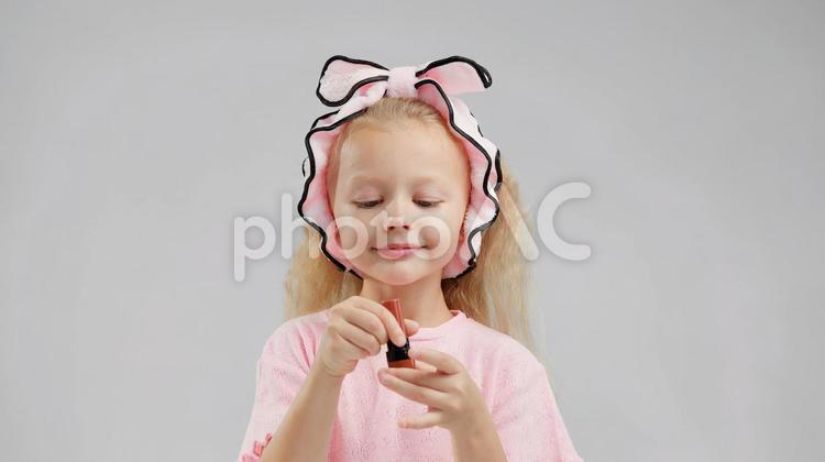 口紅を見つめるロングヘアの女の子 女の子,口紅,持つの写真素材