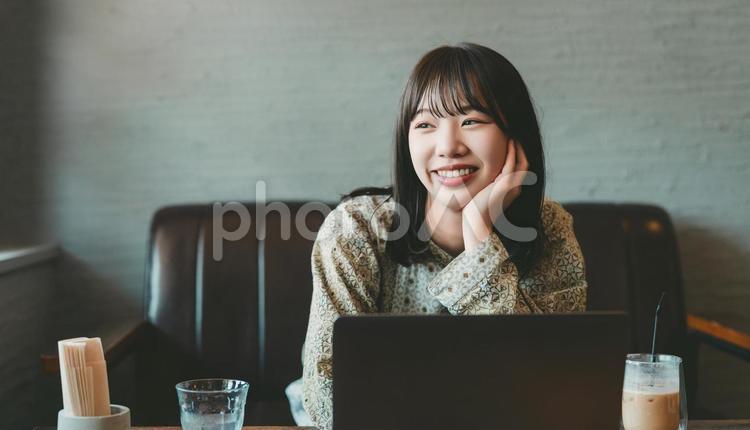 カフェでパソコンを使う若い女性 女性,笑顔,パソコンの写真素材