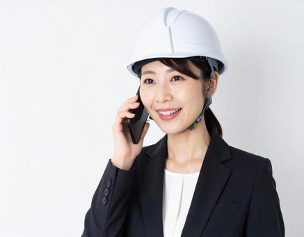 携帯電話で通話するヘルメットを被った女性の写真