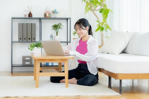 自宅でノートパソコンを操作する若い女性 若い女性,ノートパソコン,笑顔の写真素材