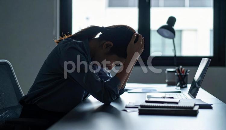 デスクで頭を抱えて悩むビジネスウーマン 悩む,女性,頭を抱えるの写真素材