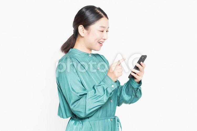スマホを操作しながら笑っている主婦 女性,主婦,スマホの写真素材