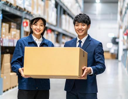 段ボールを運ぶ倉庫で作業をする若い男女 段ボールを運ぶ倉庫で作業をする若い男女の写真