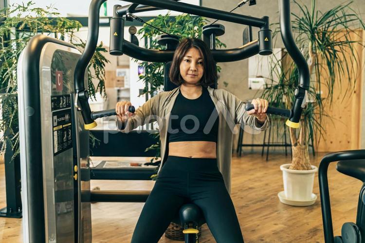 スポーツジムで体を鍛える女性（胸筋） スポーツジム,筋トレ,運動の写真素材