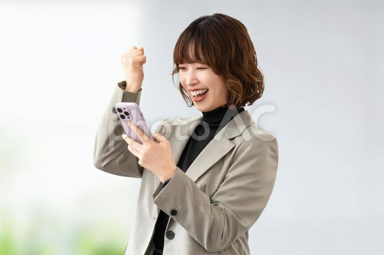 スマホを見て喜ぶ女性・ビジネスウーマン 女性,スマホ,スマートフォンの写真素材