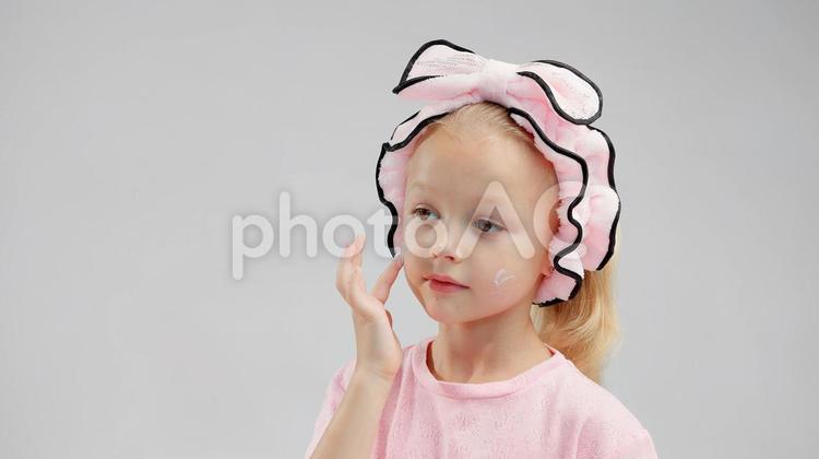 顔にクリームを付けるピンクの服の女の子 女の子,メイク,スキンケアの写真素材