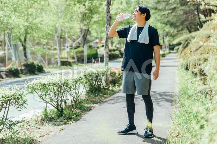 屋外でトレーニングする男性（水を飲む・笑顔・全身） 水分補給,熱中症,ドリンクの写真素材