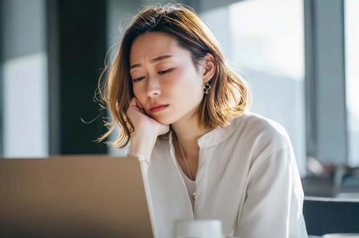 PCを前に悩むビジネス女性 PCを前に悩むビジネス女性の写真