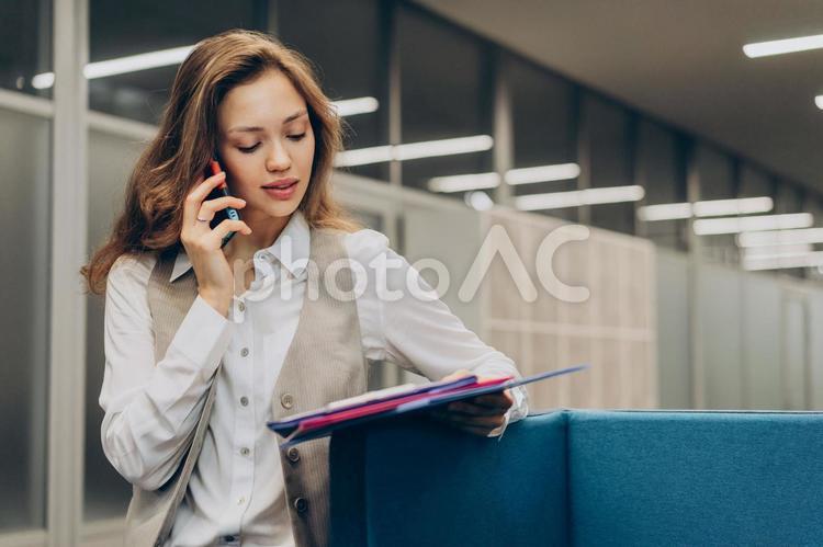 オフィスで資料を見ながら電話している女性 コワーキング,ビジネス,女性の写真素材