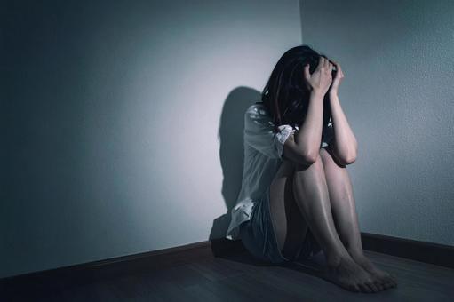 暗い部屋で恐怖に怯える女性 暗い部屋で恐怖に怯える女性の写真