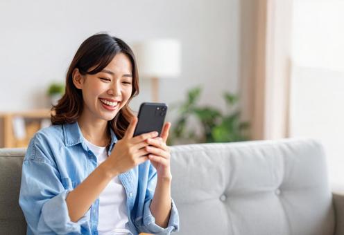 スマホの投稿を見て喜ぶ若い女性 スマホの投稿を見て喜ぶ若い女性の写真