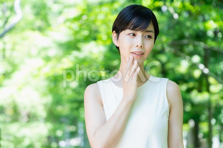 緑の中でスキンケアをする若い女性 スキンケア,ビューティー,女性の写真素材