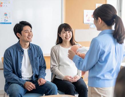 新米パパ、ママ教室で育児を学ぶ若い夫婦の写真