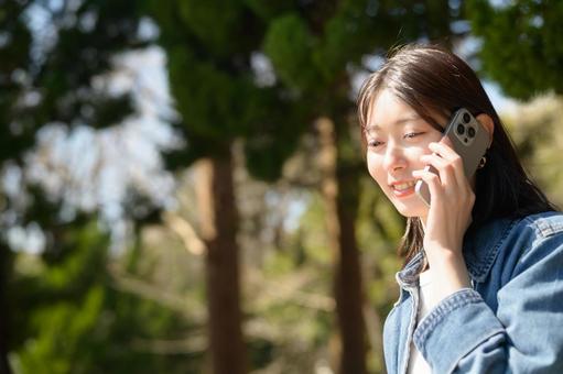 公園で電話をする女性の写真