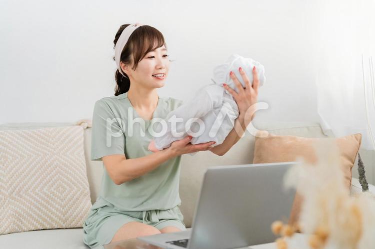 テレワークをしながら赤ちゃんをあやす女性 産休,テレワーク,育児休業の写真素材