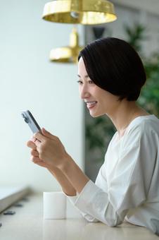 カフェでスマホを操作する日本人女性 カフェでスマホを操作する日本人女性 携帯,日本人,スマホの写真素材