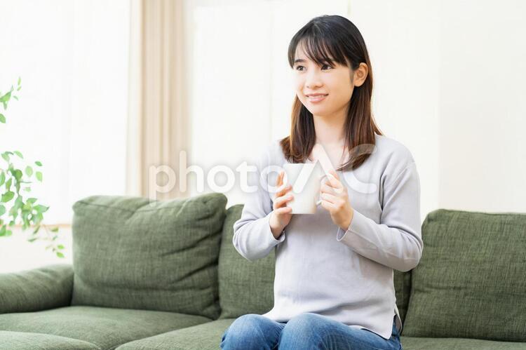 リビングのソファでコーヒーを飲む女性 女性,コーヒー,飲むの写真素材