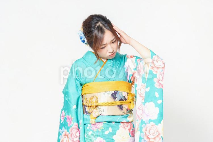 白背景の前に立って、落ち込んだポーズをする振袖を着た女性 女性,落ち込む,失敗の写真素材