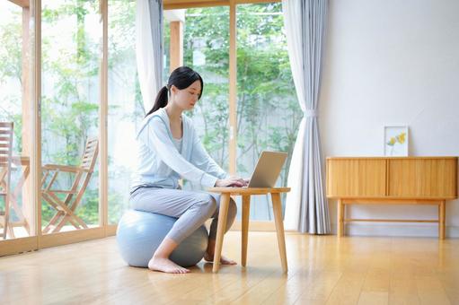 バランスボールに座りパソコン作業をする女性 女性,バランスボール,ノートパソコンの写真素材