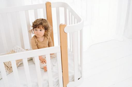ベッドの中で寂しそうな子供 ベッドの中で寂しそうな子供 赤ちゃん,かわいい,ベビーベッドの写真素材