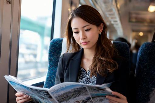 電車の中で新聞を読むビジネス女性 電車の中で新聞を読むビジネス女性の写真