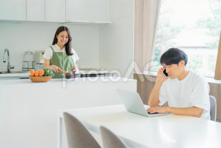 テレワークする男性と料理を作る女性 テレワーク,夫婦,料理の写真素材