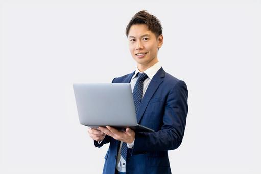 パソコンを持つ笑顔の男性ビジネスマン パソコンを持つ笑顔の男性ビジネスマン 男性,パソコン,ノートパソコンの写真素材