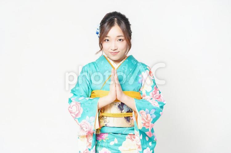 白背景の前に立って、お願いのジェスチャーをする振袖を着た女性 女性,お願い,謝るの写真素材